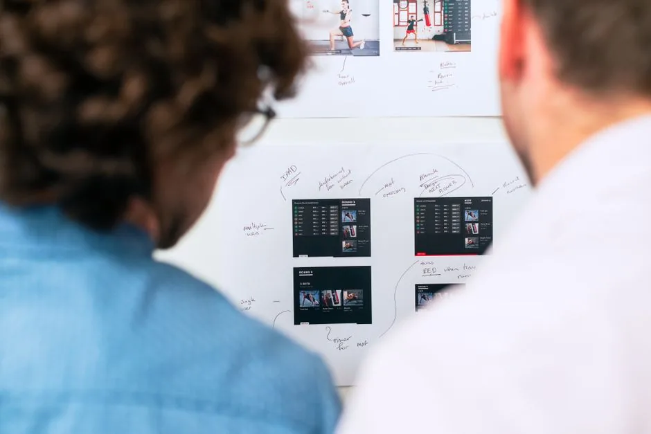 Two colleagues planning software work at a whiteboard — why enterprise AI pilots stall before production, for operations leaders